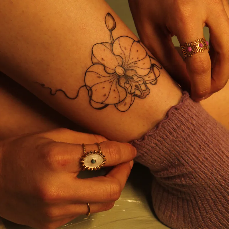 Single-needle butterfly and eye botanical piece on forearm